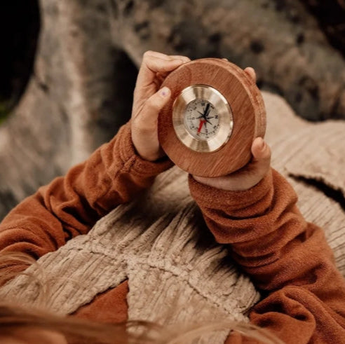 Person holding a wooden compass against a textured background