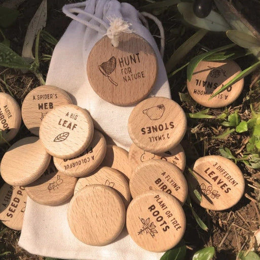 Wooden nature scavenger hunt tokens with text and illustrations on a natural background.