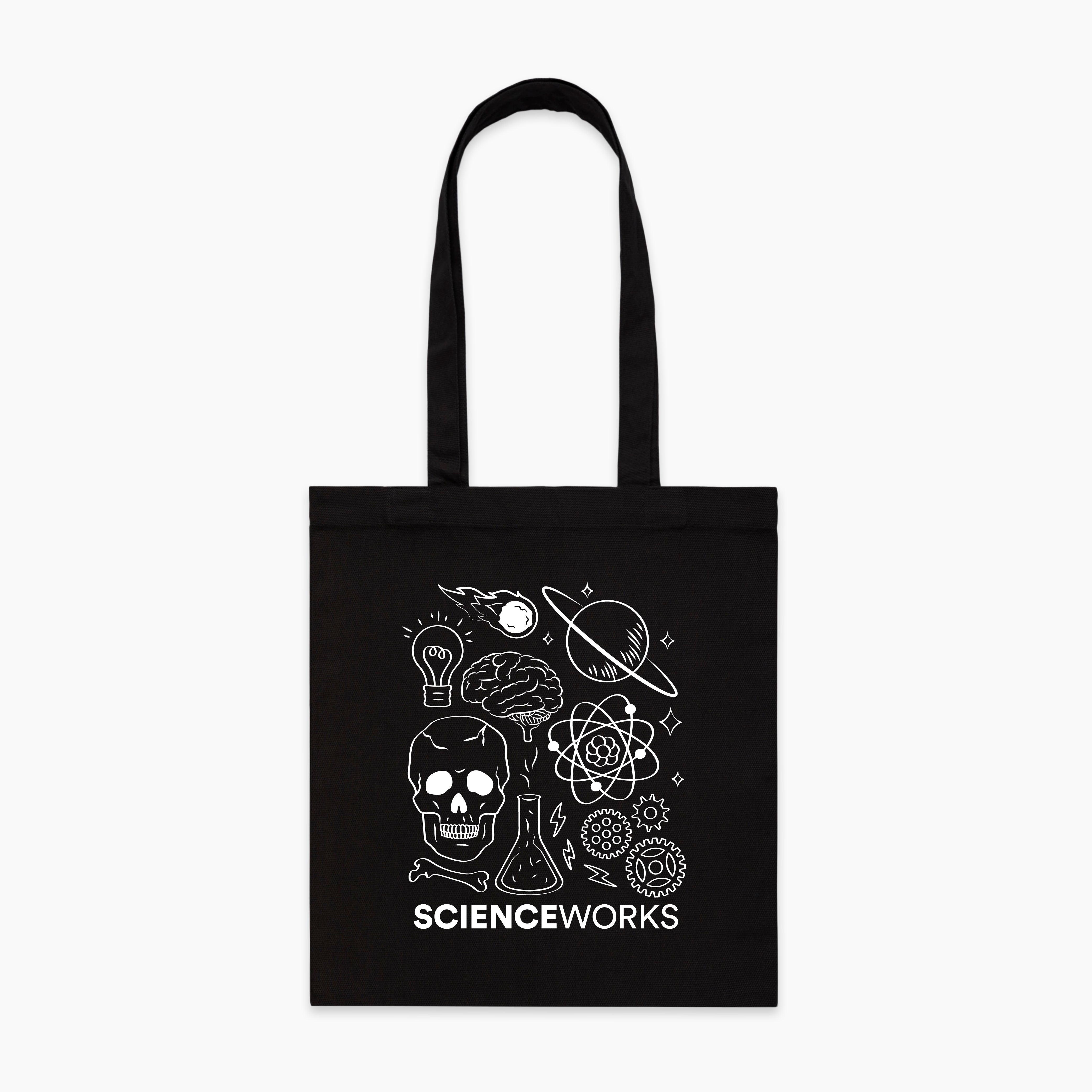 A black rectangle tote bag with a white science illustration. The image contains a lightbulb, a meteor, Saturn, a brain, an atom, stars, a skull, a beaker, a bone, three small lightning bolts, and three gears. SCIENCEWORKS is written across the bottom of the illustration.